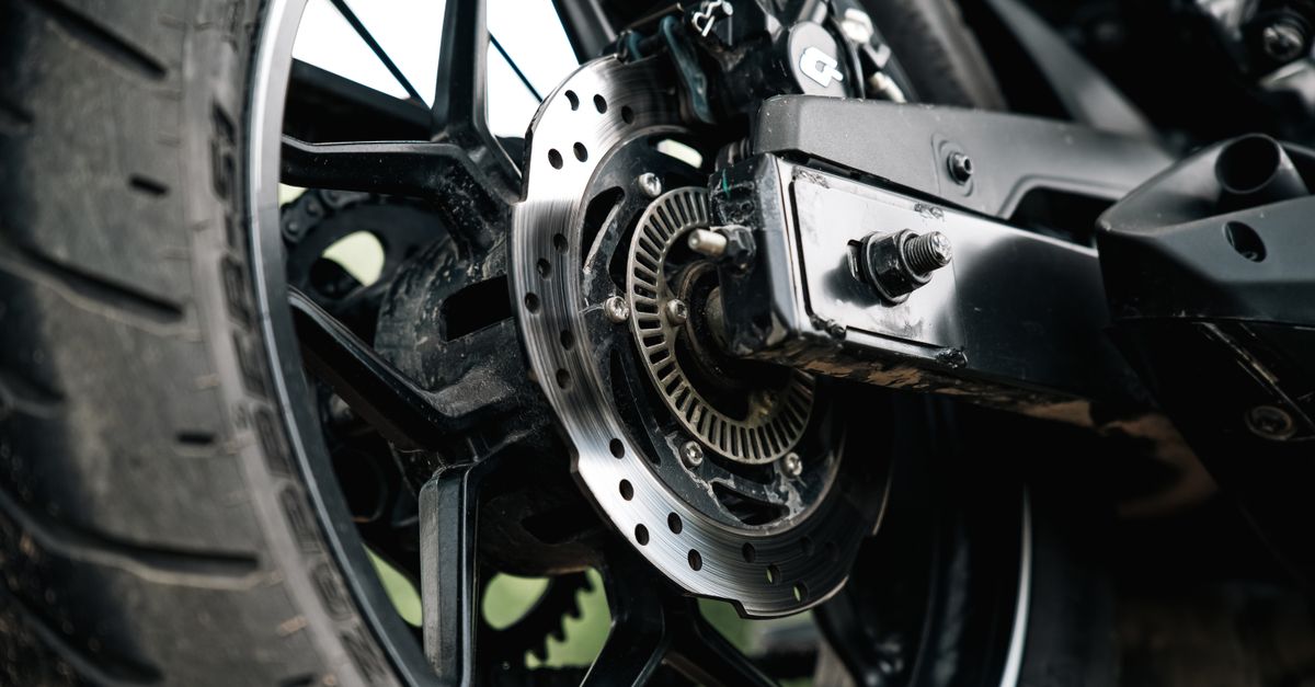 Nieuwe motorband naast een versleten motorband op een werkplaatsvloer