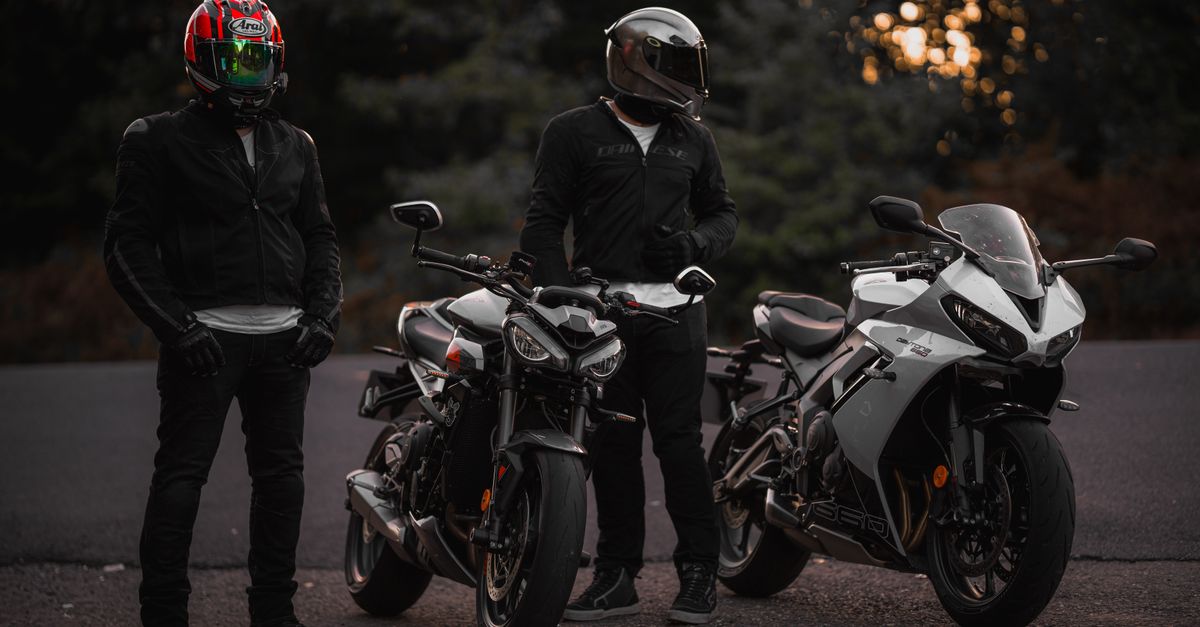 Leren en textiel motorjas naast elkaar op een werkbank