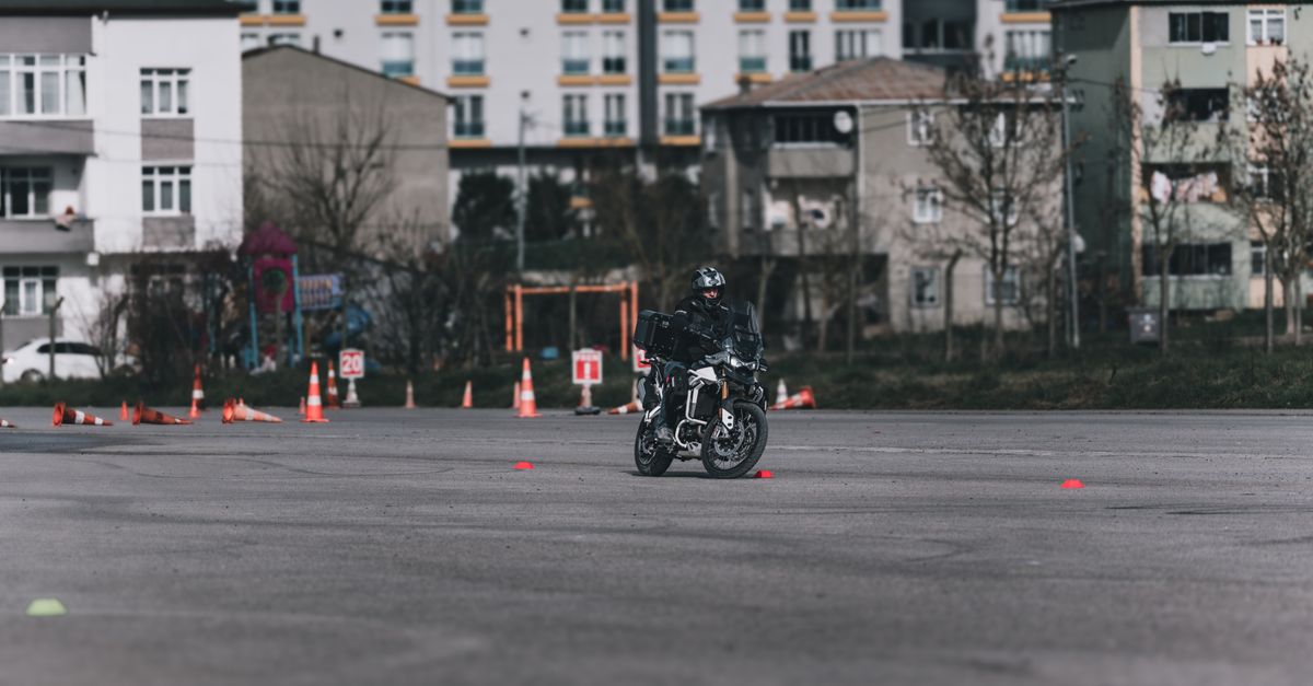 Leerling neemt motorrijles op de oefenbaan met de instructeur ernaast